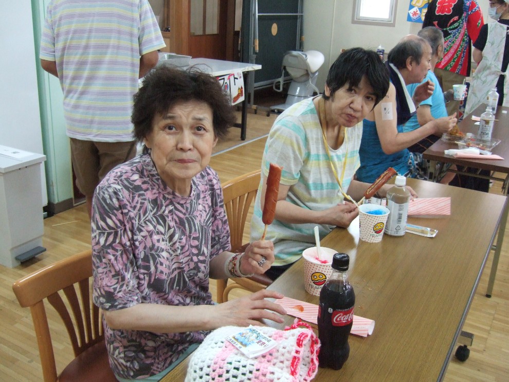 提供されたフランクフルトとかき氷を食べている二人の女性