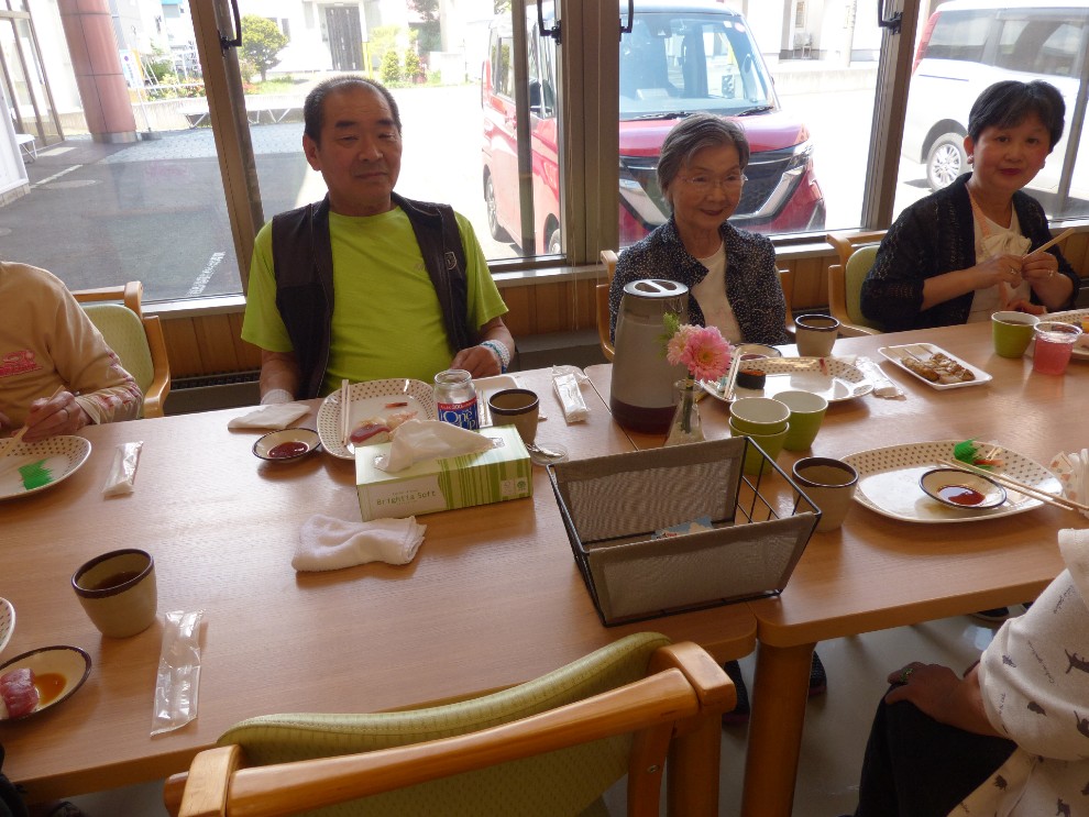 開設記念行事で提供されたお寿司を前に笑顔を見せる男性利用者様と女性利用者様
