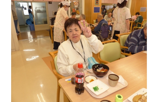 開設記念行事で提供された食事を前にピースサインをする女性利用者様