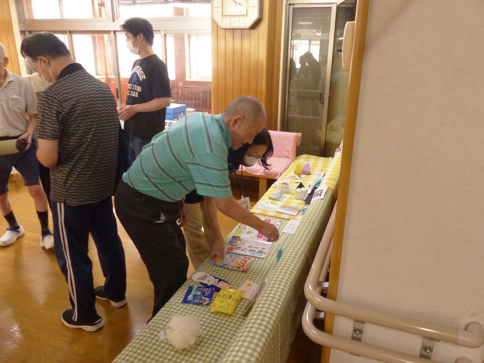 夏祭りのゲームコーナーでどの景品を選ぶか迷っている男性利用者様