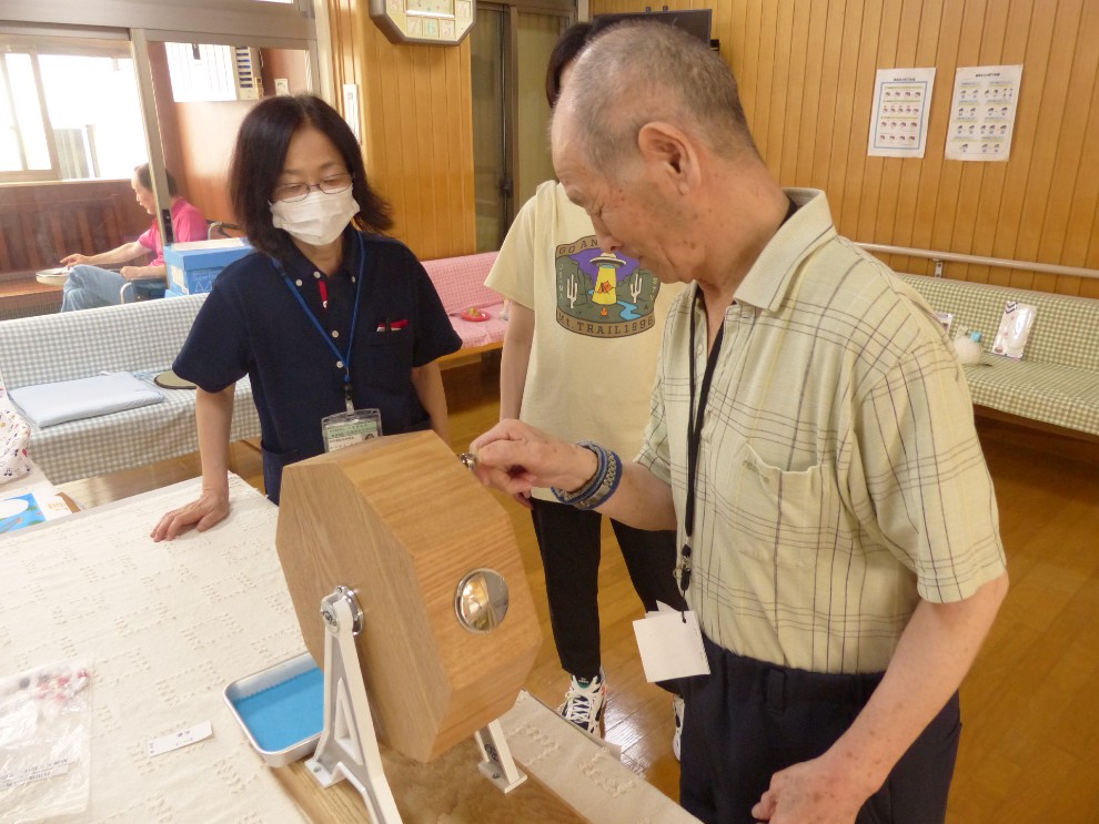 夏祭りのゲームコーナーにてガラポンを回す男性利用者様