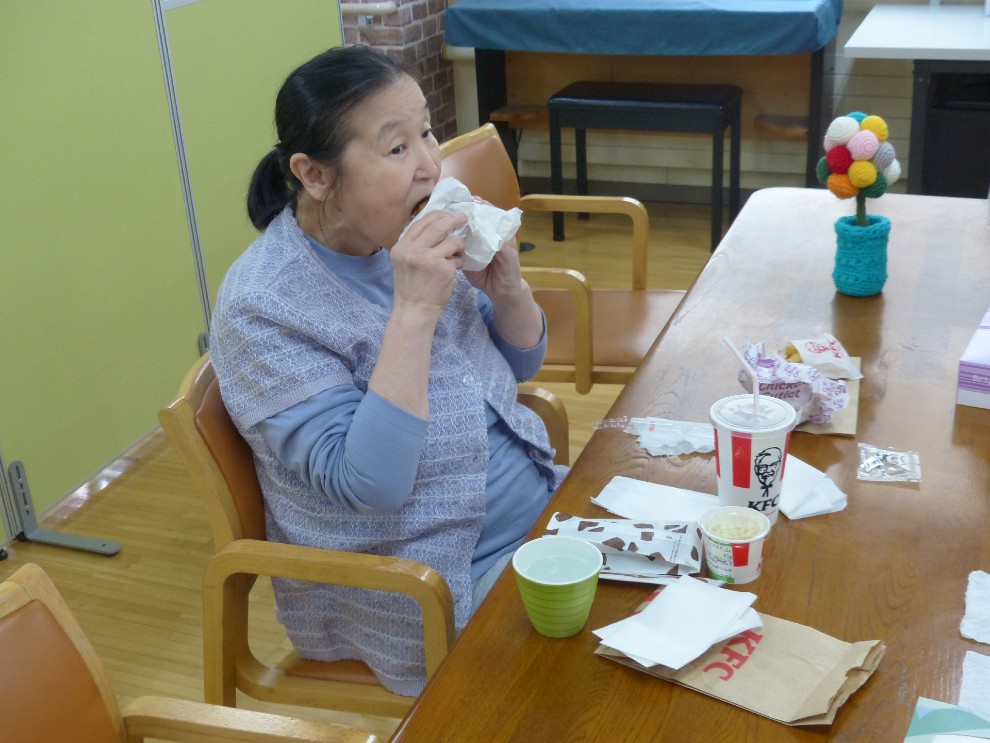 出前レクで注文したフライドチキンを食べる女性利用者様