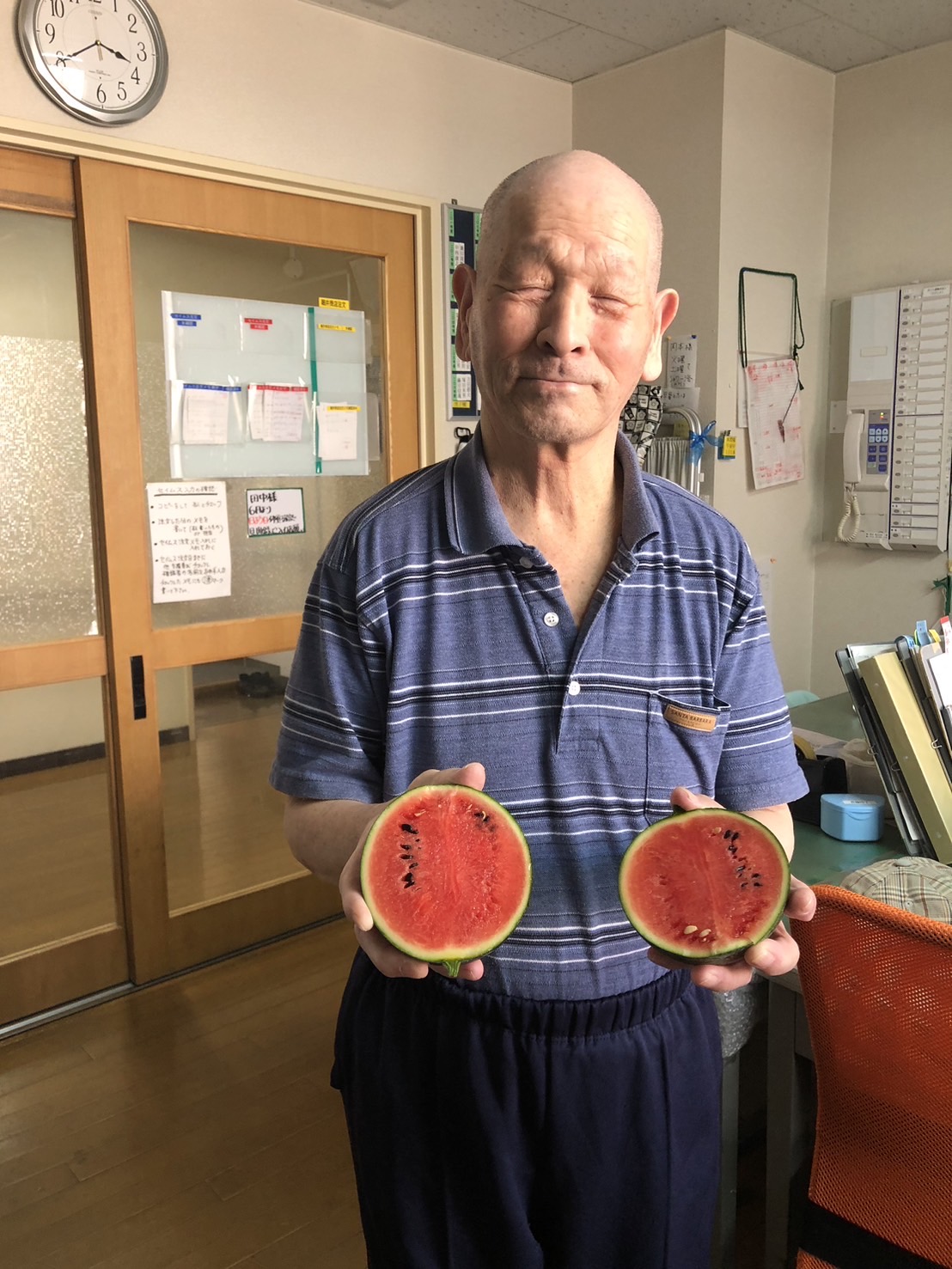 個別支援の一環として実ったスイカを切って断面を見せる男性利用者様
