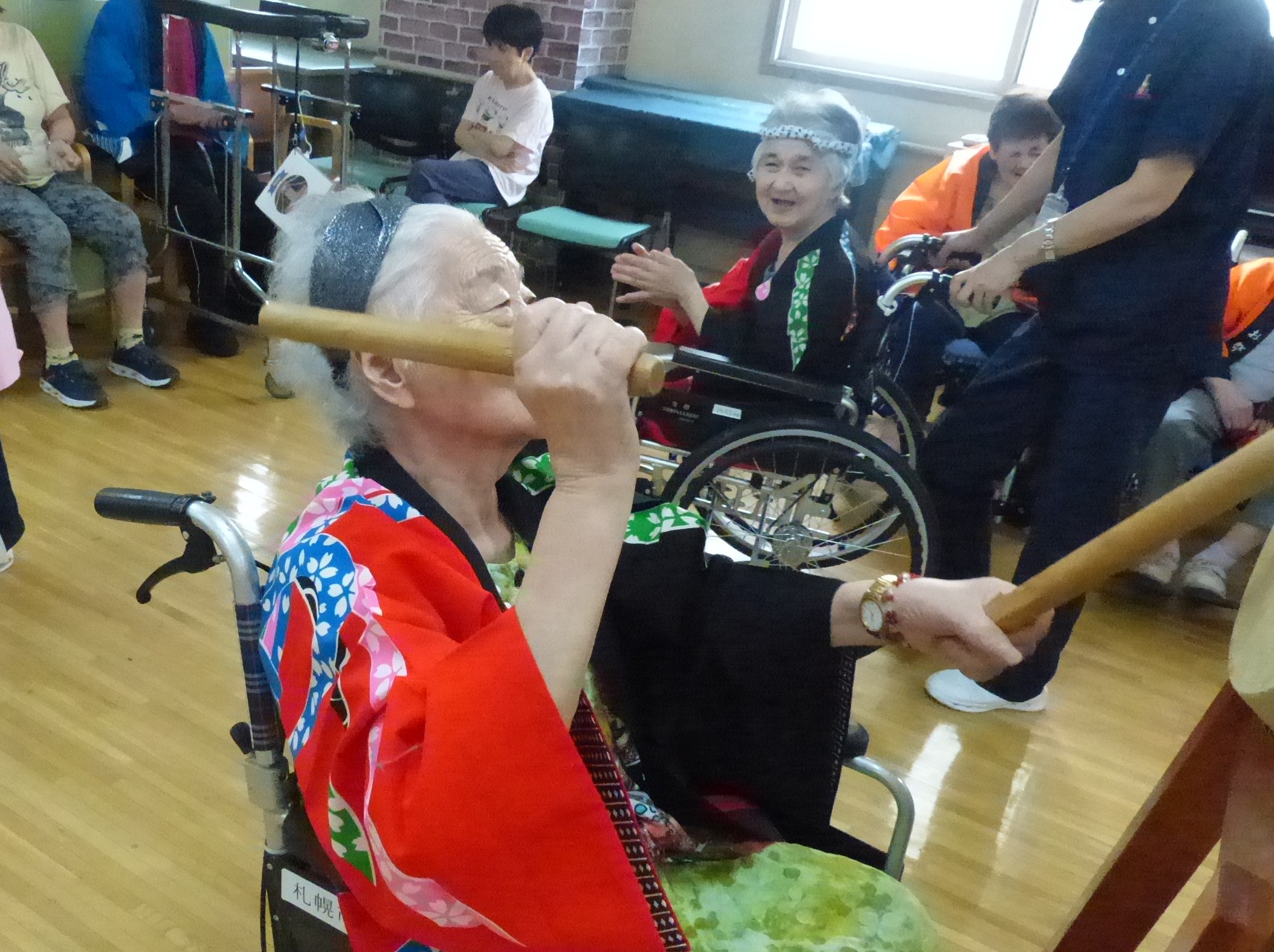 盆踊りで太鼓を叩く車椅子の女性利用者様