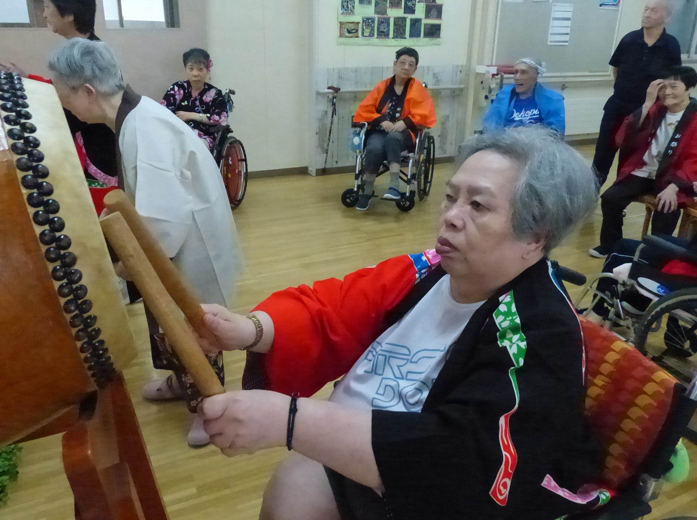 盆踊りで太鼓を叩く姿に力強さを感じる車椅子の女性利用者様