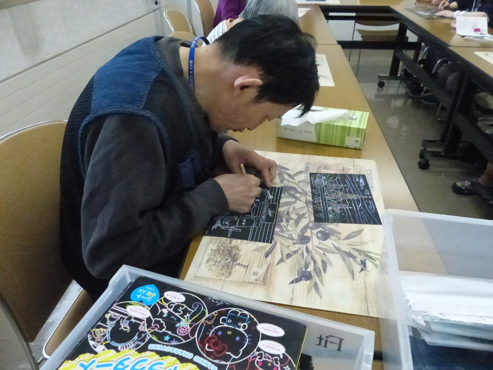 余暇クラブで真剣な眼差しで手芸品を作成する男性利用者様