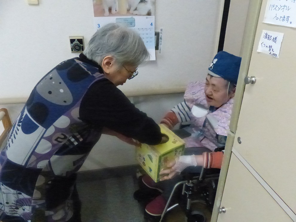 節分豆まきにて年女の利用者様から甘納豆を受け取る女性利用者様