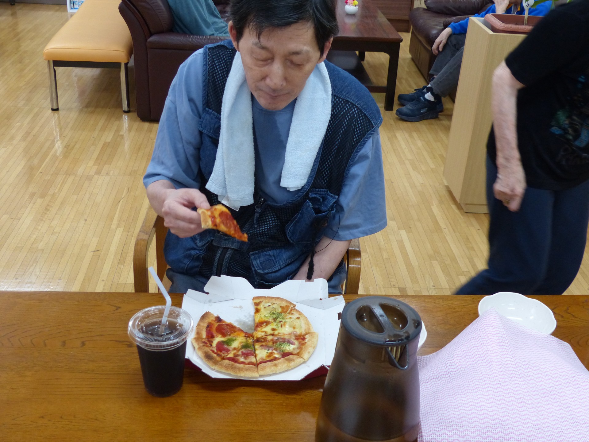 出前レクで頼んだピザを食べようとする男性利用者様