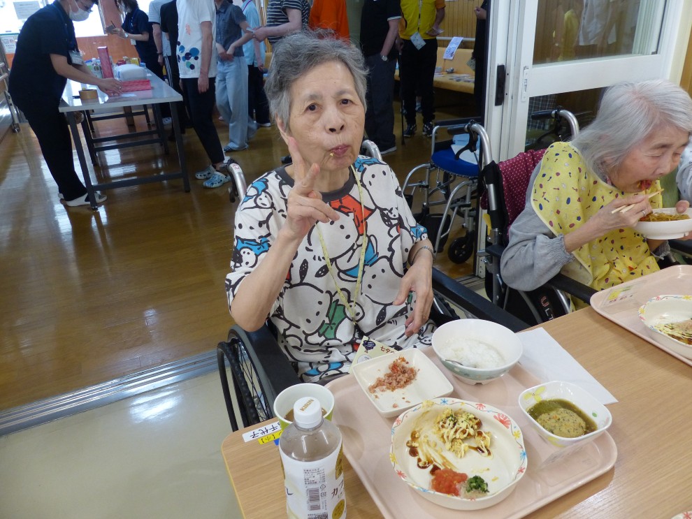 七夕まつりで提供した食事を前に笑顔とピースサインをする女性利用者様