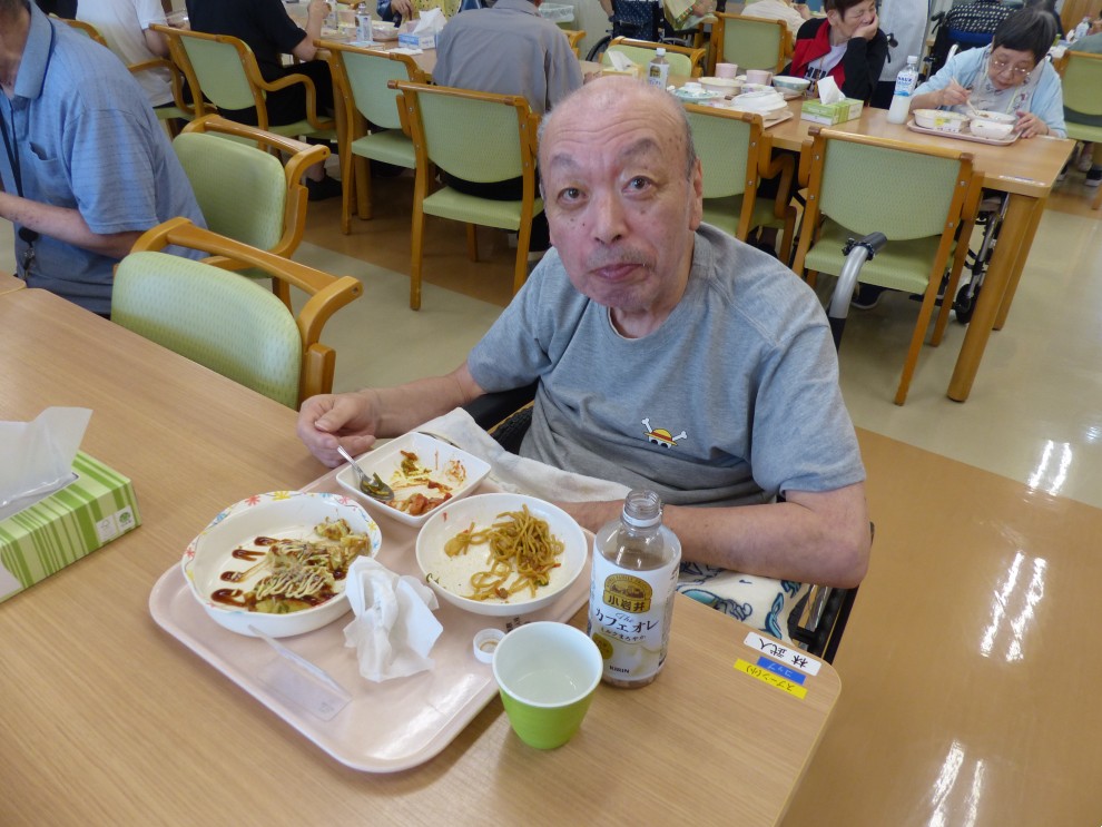 七夕まつりで提供した食事を前にカメラ目線の男性利用者様