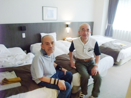 宿泊先でベッドに腰掛けて休んでいる様子