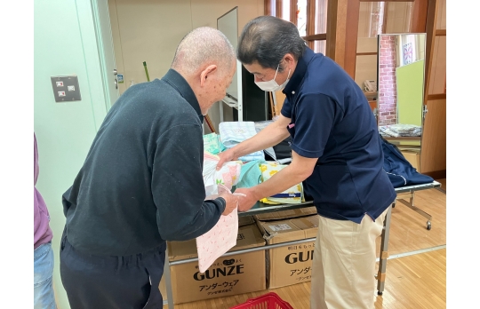施設内衣類販売で並べられた服を選んでいる男性利用者様