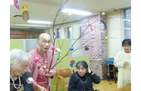 正月飾りで作成した繭玉付きの水木を披露する利用者様たち