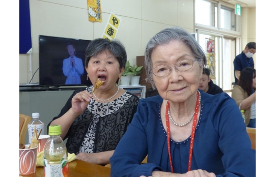 開設記念行事で提供した焼き鳥を頬張る二人の女性利用者様