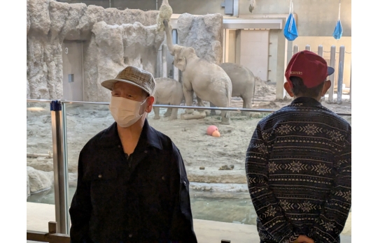 動物園レクで象を背景に記念撮影する男性利用者様